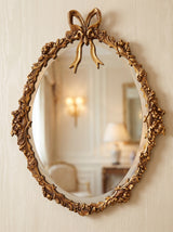 Hand-carved gilded Venetian mirror with oval Venetian frame, styled in a salon setting.